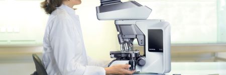 Clinical lab technician performing routine microscopy using an ergonomically designed Olympus BX46 microscope whose features help ensure proper posture and body positioning