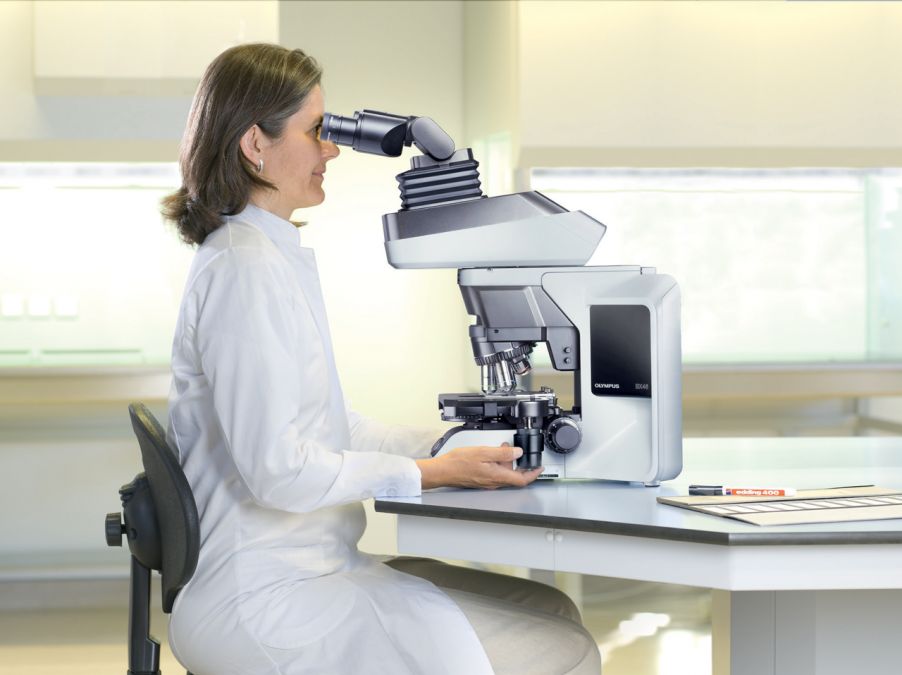 Clinical lab technician performing routine microscopy using an ergonomically designed Olympus BX46 microscope whose features help ensure proper posture and body positioning